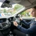 Learner driver holding the steering wheel during a driving lesson, with L plate visible, illustrating how long are driving test appointments typically take in the UK
