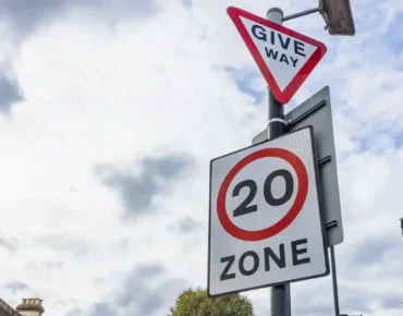 What is the most ignored traffic sign? UK give way sign and 20mph zone sign on a residential road under a cloudy sky