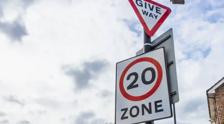 What is the most ignored traffic sign? UK give way sign and 20mph zone sign on a residential road under a cloudy sky
