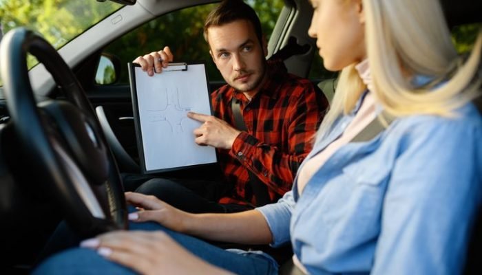 Woman and instructor with checklist in car, driving school. Man teaching lady to drive vehicle. Driver's license education